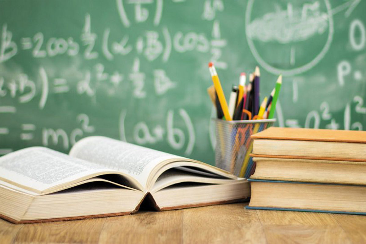 Tavolo di legno con sopra un portapenne e 4 libri